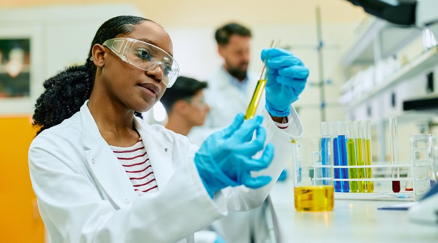 Young black scientist analyzing liquid in test tube while working in lab.